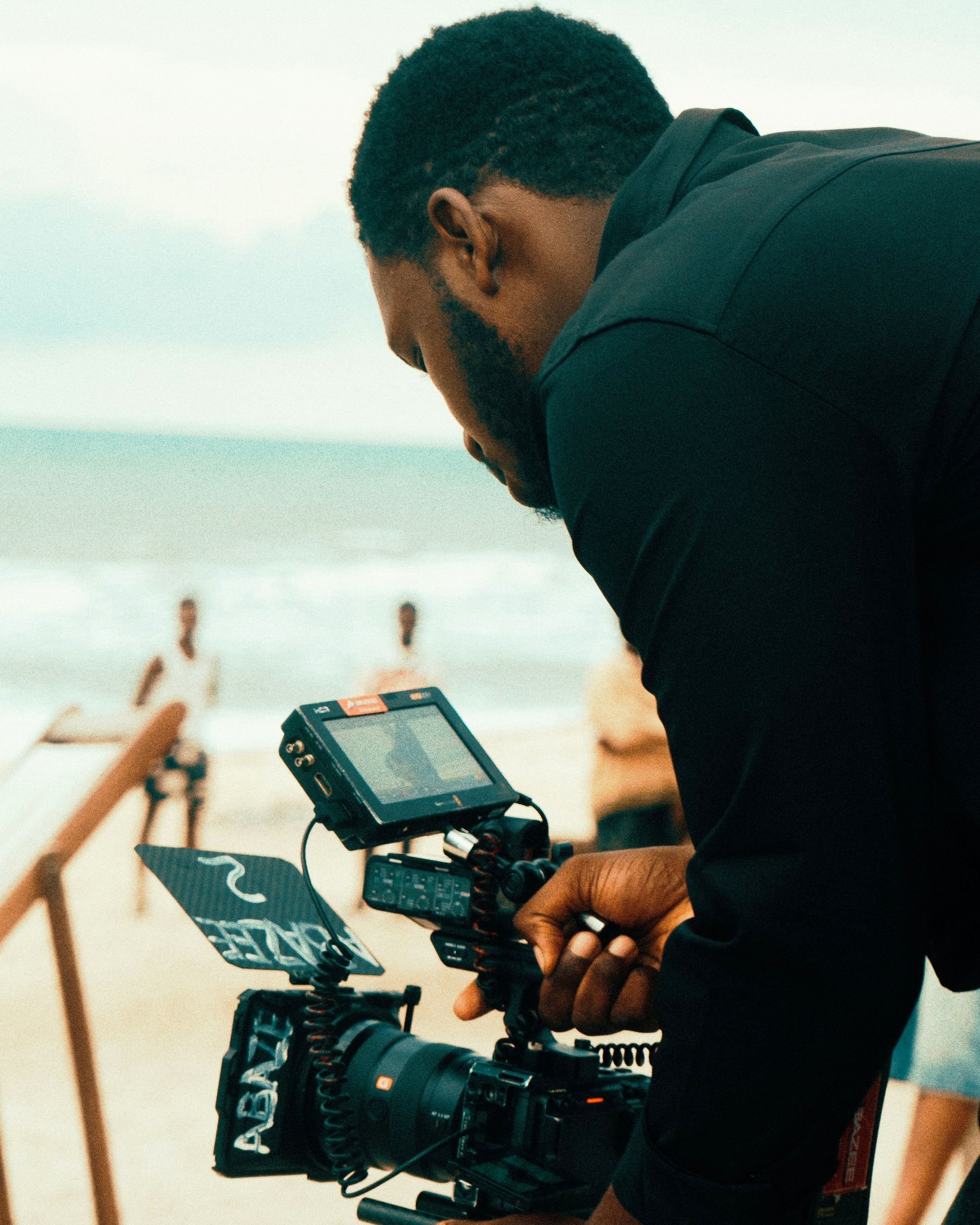 A filmmaker operating a cinema camera on a beach